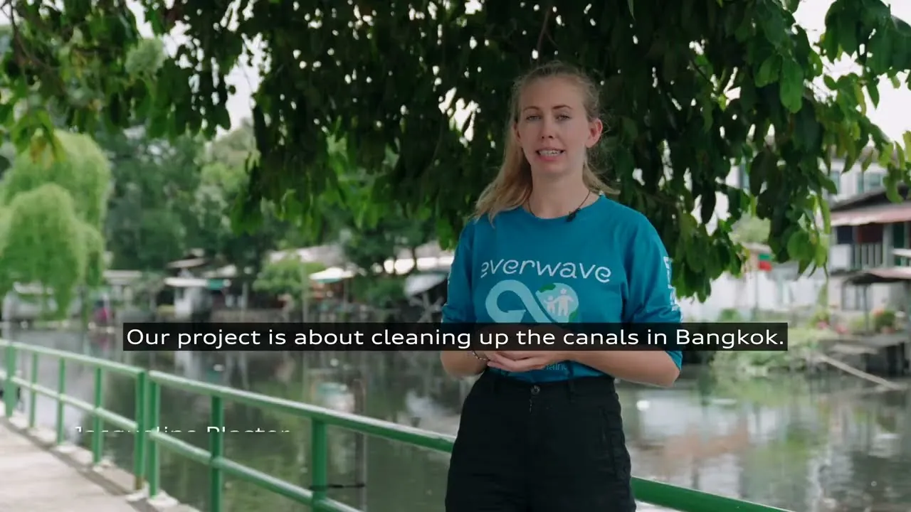 A frame from the documentary: an Everwave team member speaks beside a canal in Bangkok, with the subtitle “Our project is about cleaning up the canals in Bangkok.”