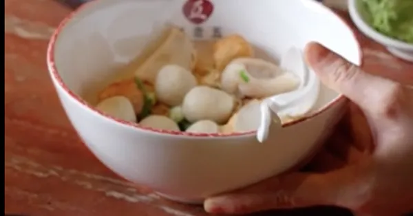 A bowl of fish balls and noodles being served