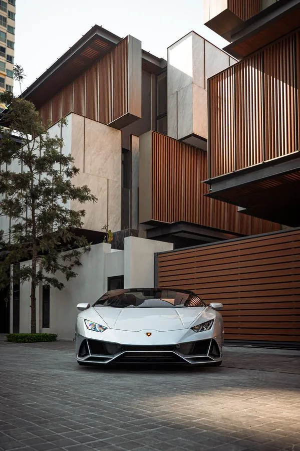 A Lamborghini Huracán parked in the courtyard of a timber-clad house