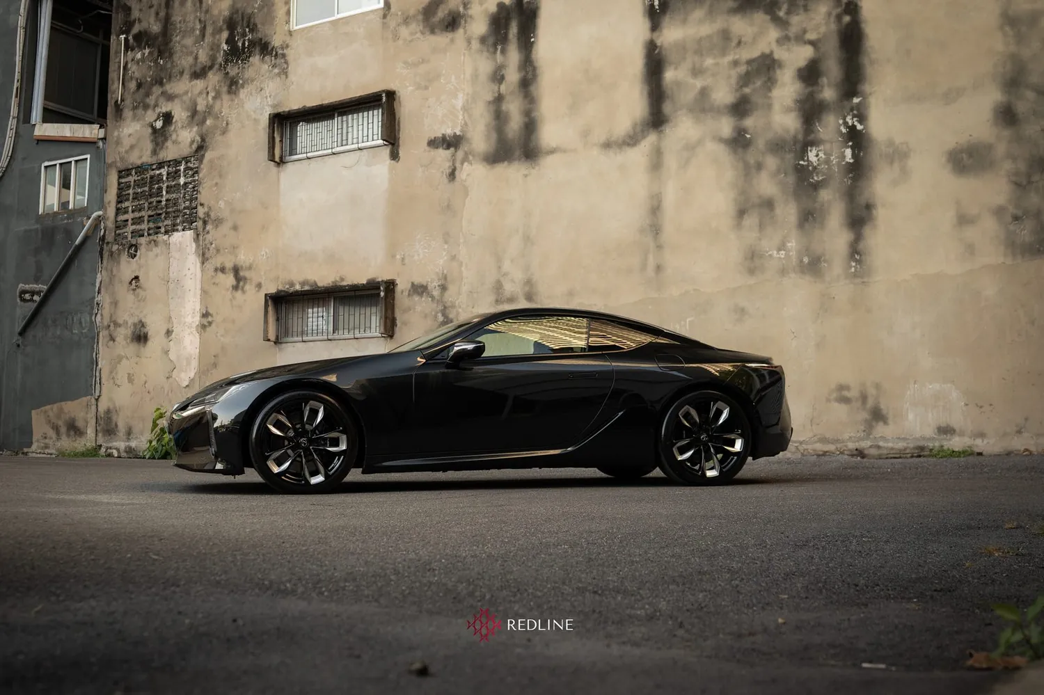 A black Lexus LC 500 against a weathered concrete wall