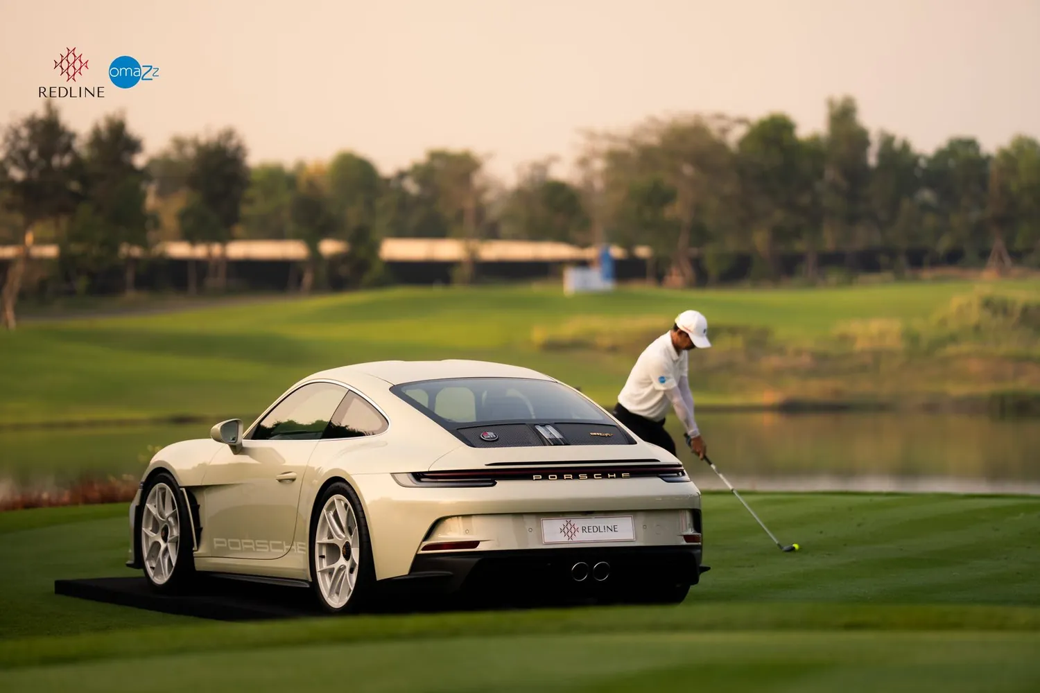 A white Porsche 911 on a golf course with a golfer behind it